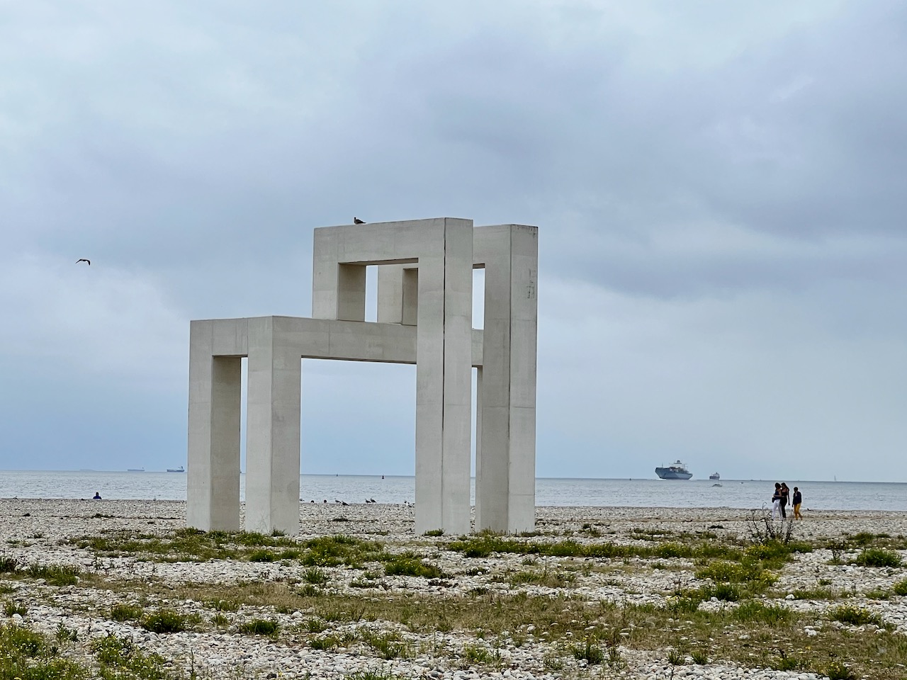 Sur la plage de galets, une arche rappelant l'ossature des batiments Perret de la ville