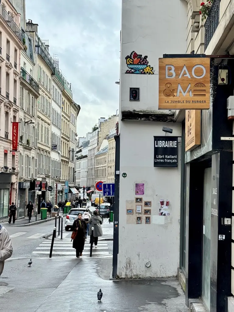 Une œuvre d’invader représentant un Space Invaders à moitié caché derrière une coupe de fruits exotiques, sur un coin de mur parisien.