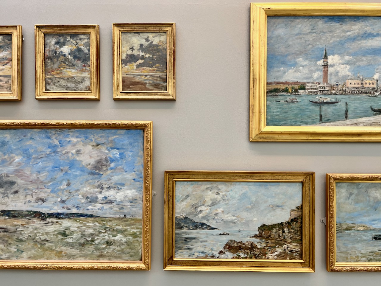 Plusieurs tableaux de paysages sur un mur, peints par Eugène Boudin