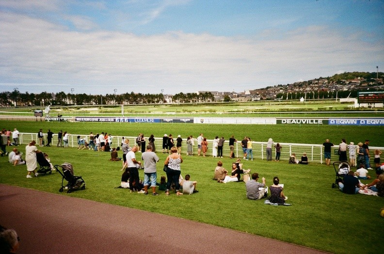 Le public se tient au bord de l'hippodrome pour regarder la course passer