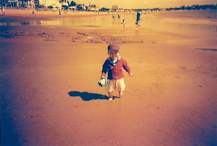 Un enfant court sur la plage avec un seau à la main