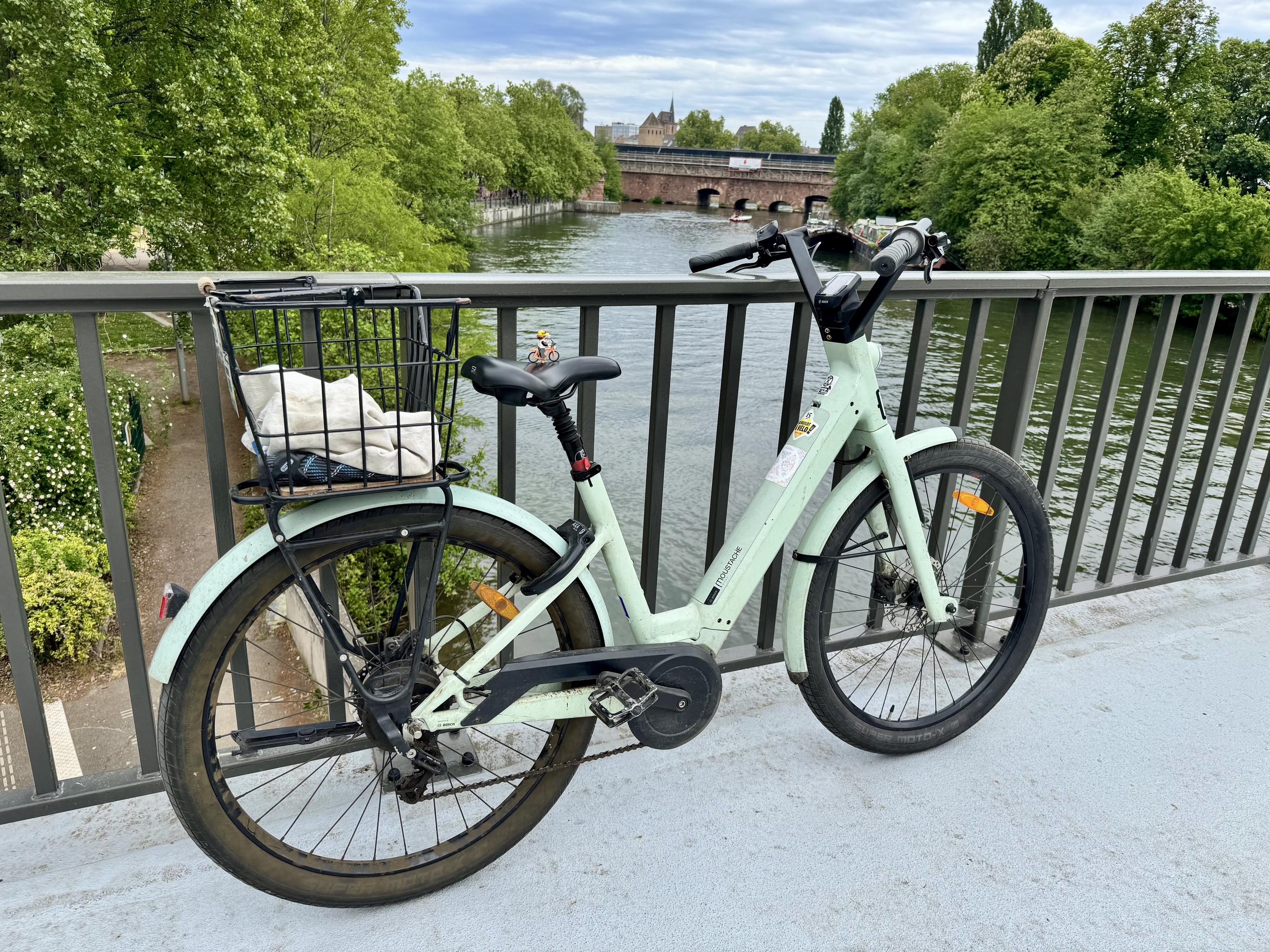 Une vélo (avec un lego sur la selle) sur un pont. Derrière on voit l’île et les ponts couverts.